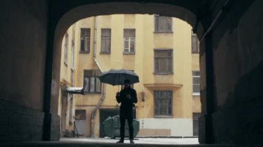 Yoğun kar yağışı altında sıcak içecek fincan ile ayakta şemsiye tutan genç adam