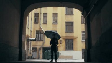 Yoğun kar yağışı altında kahve ile ayakta şemsiye tutan genç adam