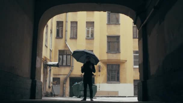 Jeune homme debout avec une tasse de café sous de fortes chutes de neige, tenant parapluie — Video