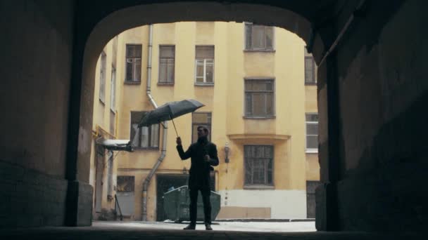 Männersilhouette mit Kaffeetasse, die unter Schneefall steht und Regenschirm öffnet — Stockvideo