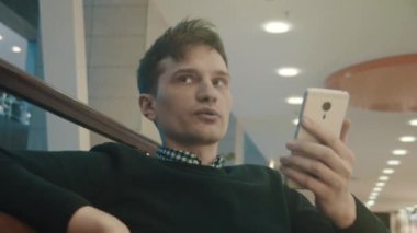 Lobi ve alışveriş merkezi, görüntülü arama yapma smartphone kullanarak delikanlı. Portre