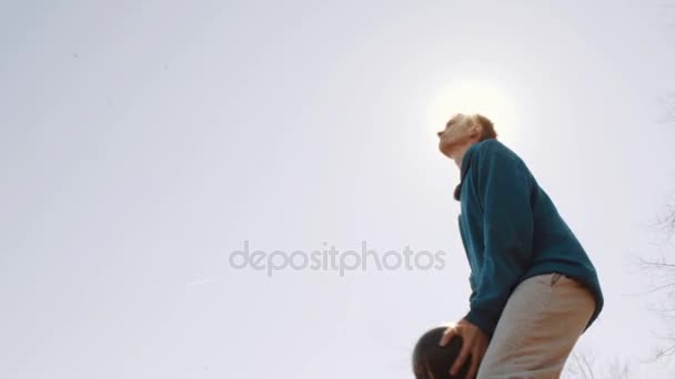 Soccer player jumps up and heads the ball at city park. Slow motion. Lens flare — Stock Video