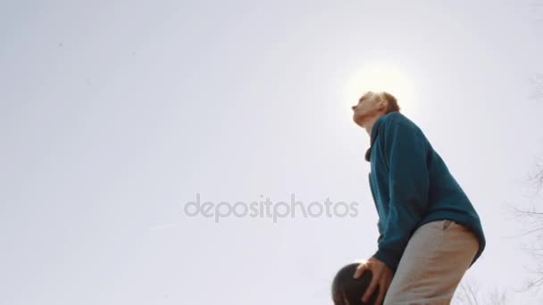 Jogador de futebol salta e dirige a bola no parque da cidade. Movimento lento. Inflação da lente — Vídeo de Stock