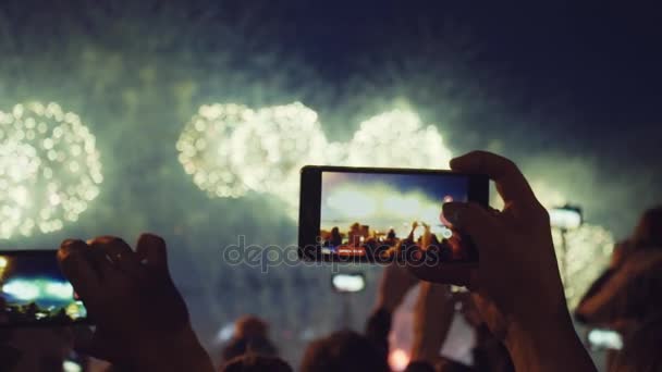 Manos de la gente tomando fotos de fuegos artificiales en el teléfono inteligente. Primer plano. Movimiento lento — Vídeos de Stock