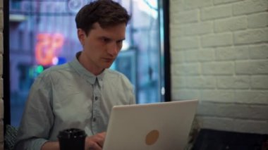 İnternet kafede oturan alışveriş için laptop ve kredi kartı kullanan genç adam.