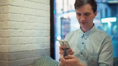 İnternetten alışveriş için Smartphone ve kredi kartı kullanarak kafede, oturan genç adam