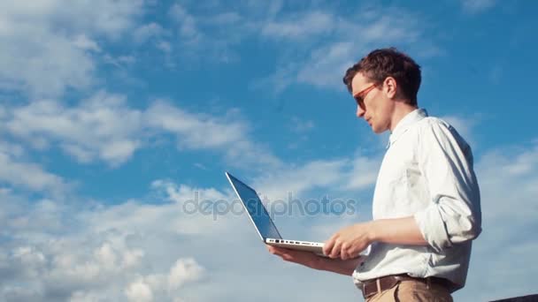 Joven hablando en videollamadas con portátil de pie al aire libre. Día de verano — Vídeos de Stock