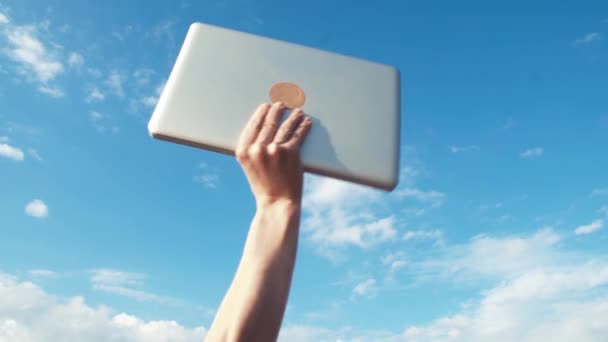 Mannenhand verhogen laptop omhoog. Blauwe hemel op achtergrond. Succes, prestatie gebaar — Stockvideo