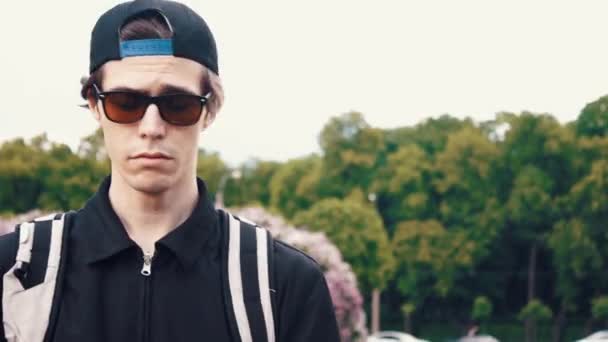 Junger Mann in Sonnenbrille und Sportkleidung mit Laptop im Park. Sommertag — Stockvideo