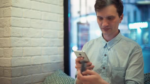 İnternetten alışveriş için Smartphone ve kredi kartı kullanarak kafede, oturan genç adam — Stok video