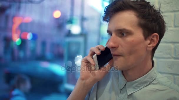 Szczęśliwy młody mężczyzna rozmowa na telefon i świętować sukces w kawiarni w godzinach wieczornych. — Wideo stockowe