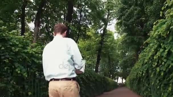 Young man going at park using laptop receiving good news and celebrating success — Stock Video