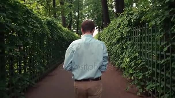 Молодой человек празднует успех в парке после получения хороших новостей — стоковое видео