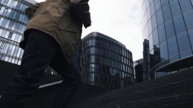 İş Merkezi için merdivenlerden yukarı geliyor takım elbise ve yağmur ceketli genç işadamı.