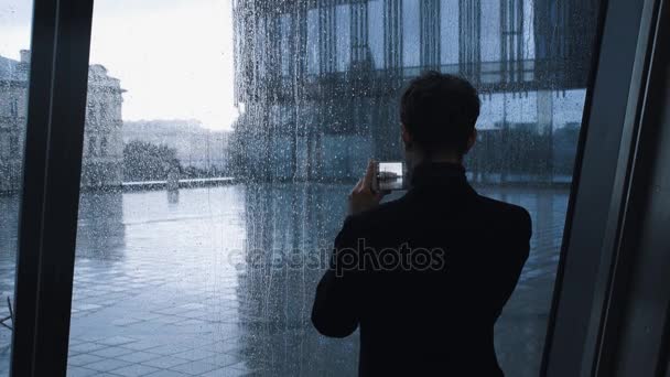 Молодий чоловік робить фото зі смартфоном у приміщенні будівлі бізнес-центру — стокове відео