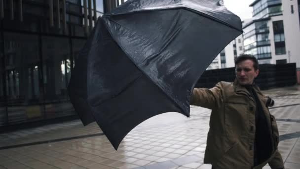 Young man in jacket with umbrella standing near the business centre building — Stock Video