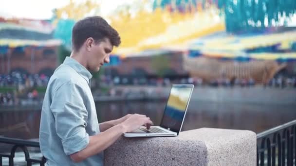 Hombre joven caucásico usando portátil de pie al aire libre. Día de verano — Vídeos de Stock