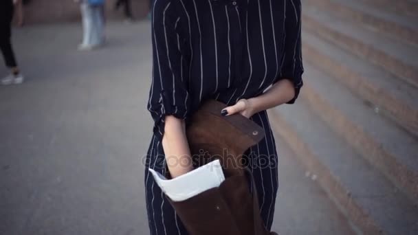 Junges Mädchen sucht etwas in ihrer Tasche, die im Stadtpark steht — Stockvideo
