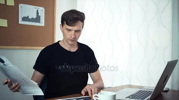 Libero professionista guardando i dati stampati e analizzando i grafici presso l'home office — Video Stock