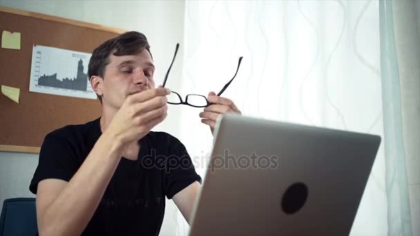 Freelancer sostiene en las manos gafas, mira la pantalla del ordenador portátil . — Vídeos de Stock