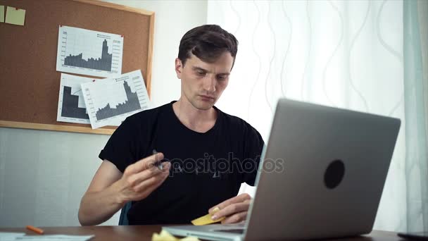 Young man writing percent sign on sticky note attaching it to board at office — Stockvideo