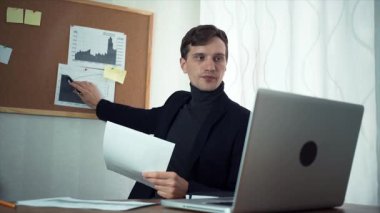 Finansal analist basılı grafikler gösteren dizüstü kullanarak istemci ile sohbet