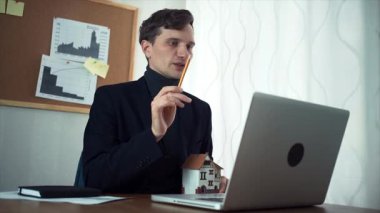 Genç dizüstü kullanarak müşteri ile görüntülü görüşme sahip emlakçı