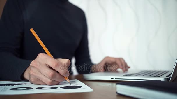 Male hands making note with pencil at printed analyzing graphs — Stock Video