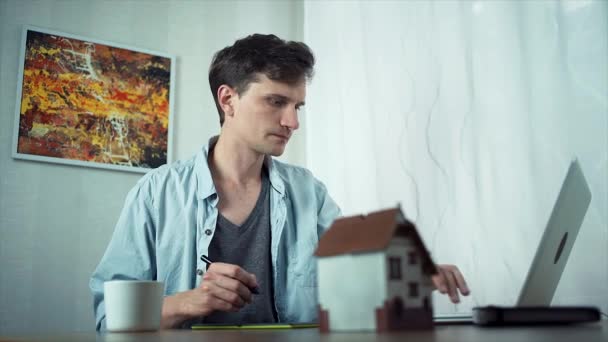 Casual vestido cara usando tablet gráfico criando projeto de habitação no laptop — Vídeo de Stock