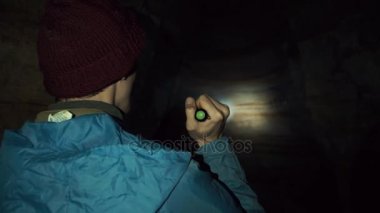 Genç explorer mağarada el feneri ile yürüme. Derin karanlık çevresinde