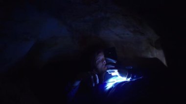 Yakından mağara el feneri ile delik toprağa üzerinde döşeme smartphone kullanarak uzun yürüyüşe çıkan kimse