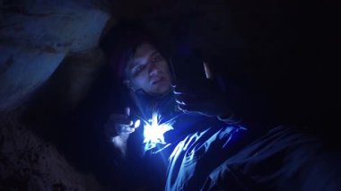 Gezgin zor nefes el feneri ile dar mağara üzerinde döşeme smartphone kullanarak