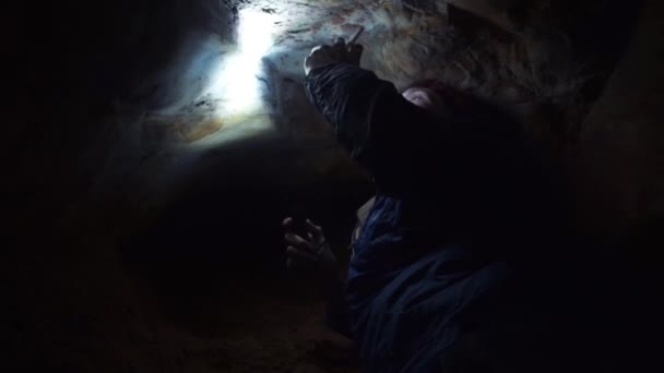 Uomo utilizzando smartphone posa a terra in grotta molto stretta con torcia a mano — Video Stock