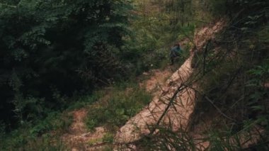 Bitkiler ve moss ile büyümüş yamaç tarafından üst kadar ulaşan genç uzun yürüyüşe çıkan kimse