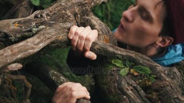 Genç adam tarafından Ağaçların kökleri için tutunmuş Yamaç yukarı tırmanıyor