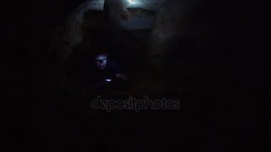 Adam dışarı doğru el feneri ve smartphone elinde olan mağara içindeki delikten tırmanıyor.