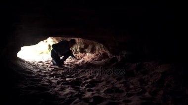 Genç adam karanlık mağaranın odasına düşük taş tonoz ve yürüyüş altında karanlık girer.