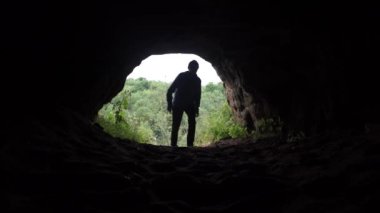 Genç explorer düşük taş tonoz ve yürüyüş altında karanlık mağaranın karanlığa girer