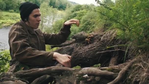 Jeune homme grimpe haut par la pente accroché aux racines des arbres — Video