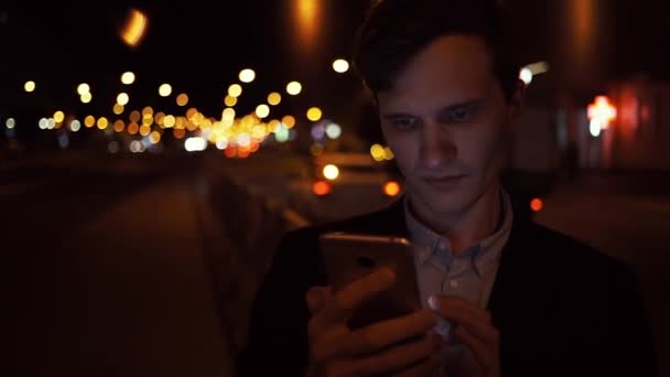 잘생긴 젊은 남자 스마트폰 입고 캐주얼 정장 자 켓 야외 미소를 사용 하 여 — 비디오