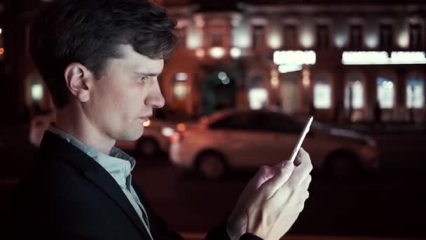 Jungunternehmer nachts mit Smartphone auf belebter Stadtstraße — Stockvideo