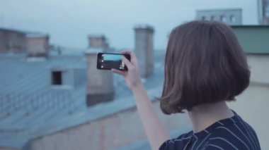 Çatıda oturan smartphone kullanarak genç kız alarak fotoğraf.