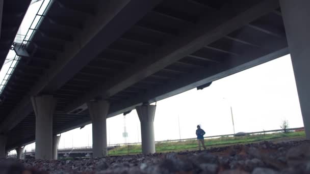 Uzun yürüyüşe çıkan kimse köprü altında yürüyen sırt çantası ile. Arka plan, şehir yolda araba trafik — Stok video