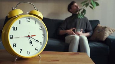 Dizlerinin üzerinde pot bitki ile evde kanepede oturan genç adam