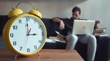 Evde kitap okuma dizlerinin üstünde laptop ile kanepede oturan genç adam
