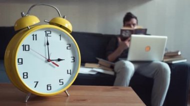 Evde kitap okuma dizlerinin üstünde laptop ile kanepede oturan genç adam