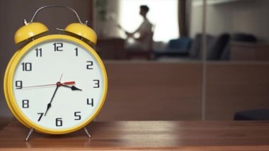 Büyük sarı saat rafa geçiyor. Dizüstü bilgisayar kullanan büyük ayna adam yansıma