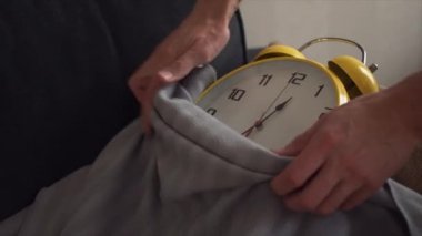 Erkek el kapsayan bir battaniye ile kanepede yatan saat