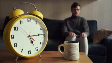 Genç adam uzakta belgili tanımlık sergen kanepede oturan içme çay fincan alır