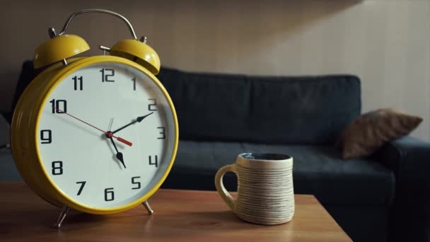 Grande relógio amarelo está correndo enquanto está perto da xícara de chá quente na prateleira — Vídeo de Stock